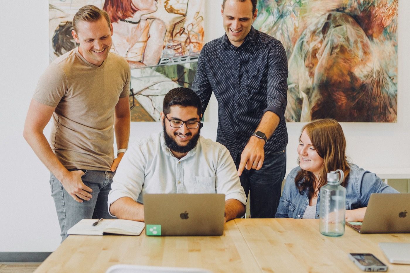 Vier collega's lachen samen rond een laptop